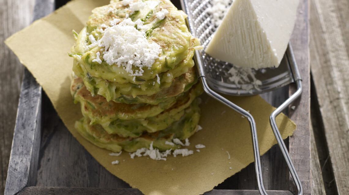 Soffici pancakes agli asparagi impilati l'uno sopra all'altro con ricotta dura grattugiata sopra su carta