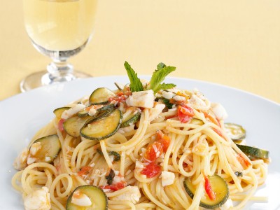ricetta Spaghetti con sugo di branzino, accompagnati da zucchine e foglioline di menta fresca.