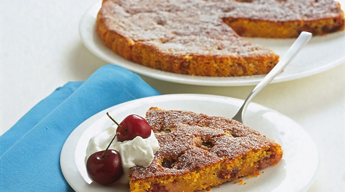 Fetta di torta di carote con ciliegie e panna su piatto