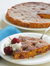 Fetta di torta di carote con ciliegie e panna su piatto