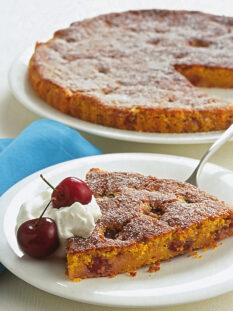 Fetta di torta di carote con ciliegie e panna su piatto