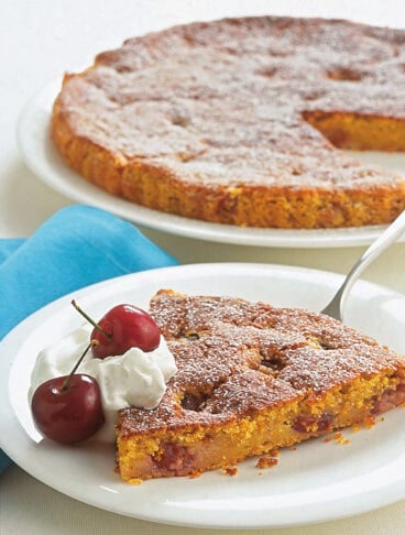 Fetta di torta di carote con ciliegie e panna su piatto