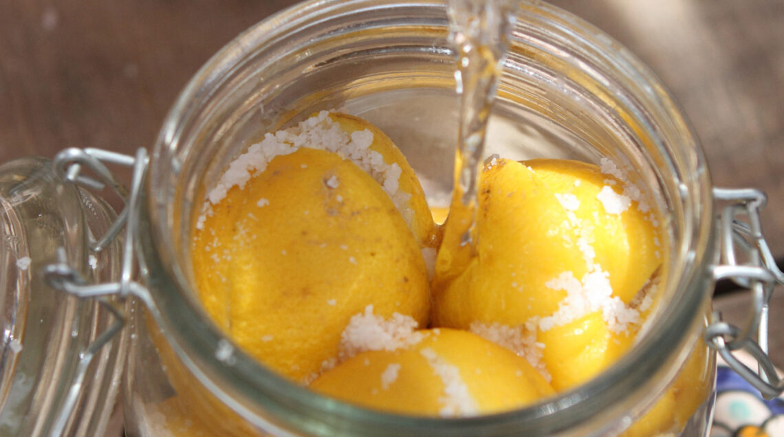 Preparazione dei limoni in conserva sotto sale in un barattolo di vetro, metodo tradizionale per conservare gli agrumi.