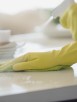 Close-up of woman's hands in rubber gloves using spray cleaner.