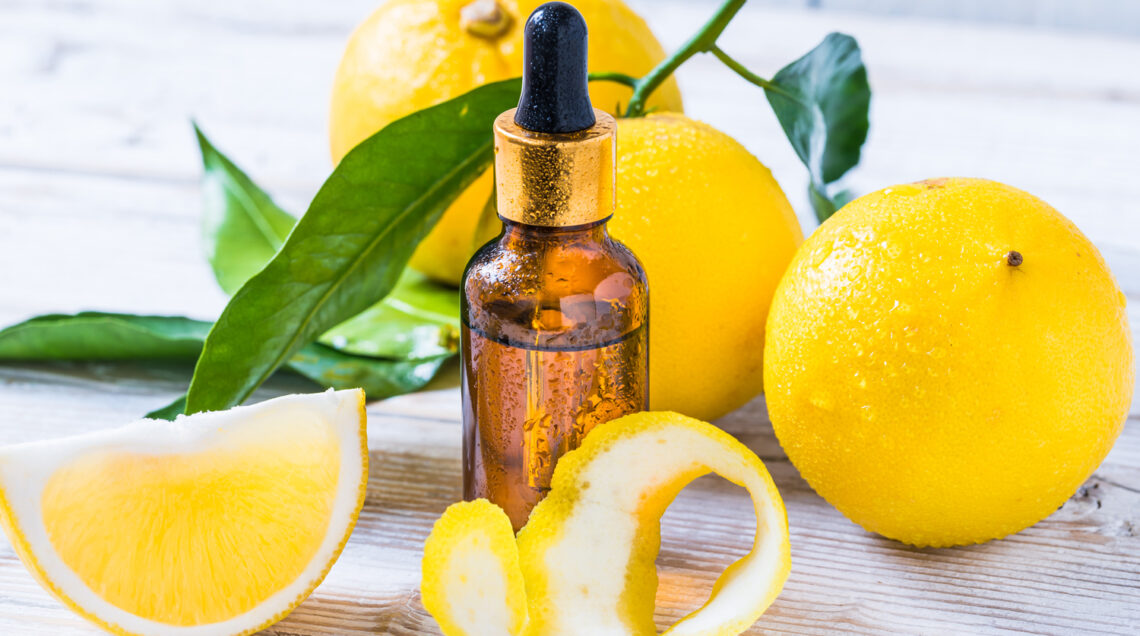 Olio essenziale di limone in boccetta con scorza di limone e limoni con foglie