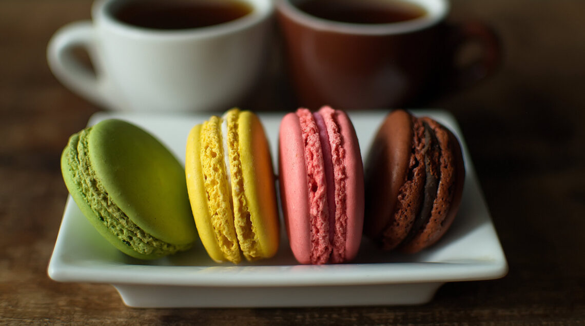 Multi-colored macaroons on a wooden tray. Pink, yellow and green macaroon.