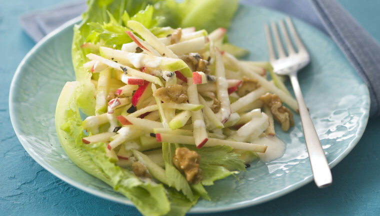 insalata waldorf in un piatto piano azzurro con una forchetta a lato