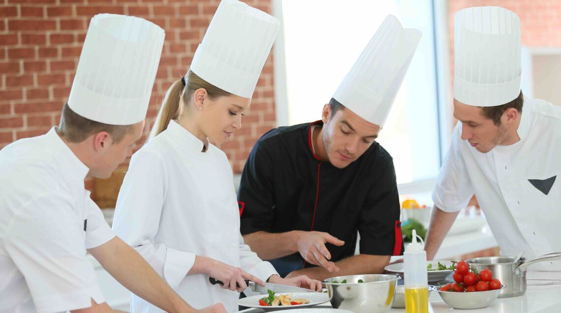 Chef training students in restaurant kitchen