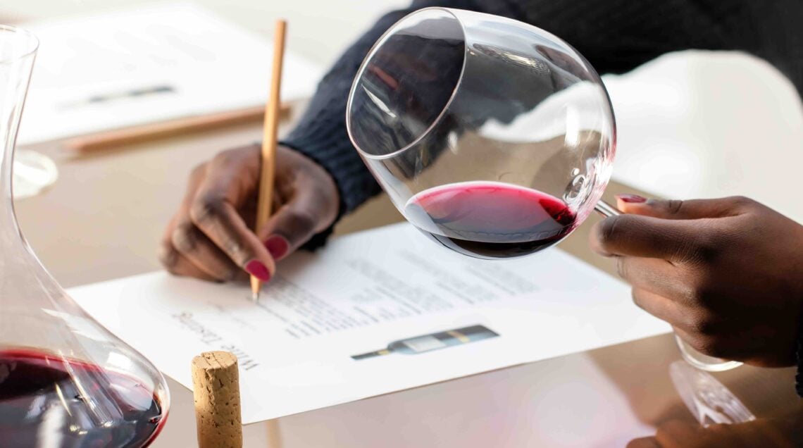 Enologist evaluating red wine at wine tasting.