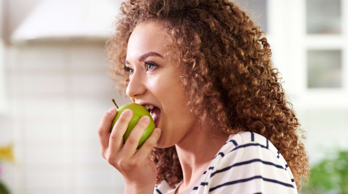 Woman taking a big bite of an apple