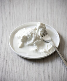 Primo piano di stracciatella fresca e cremosa servita su un piatto con una forchetta