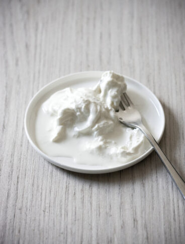 Primo piano di stracciatella fresca e cremosa servita su un piatto con una forchetta