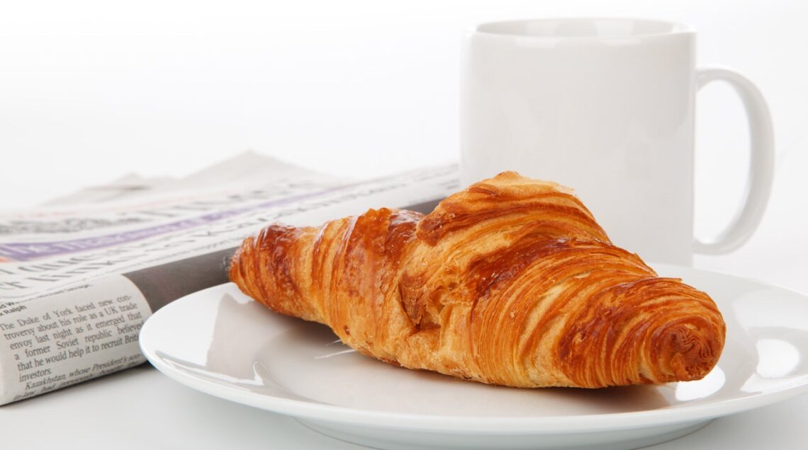 croissant newspaper and tea