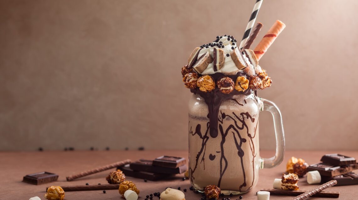 Chocolate milkshake with ice cream, with whipped cream, marshmallow, sweet popcorn, cookies, waffles