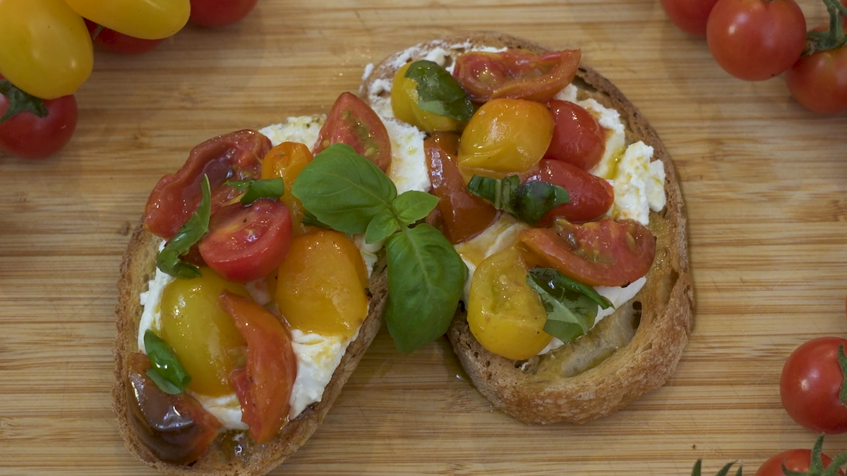Bruschetta con pomodori misti saltati, caprino, basilico e miele