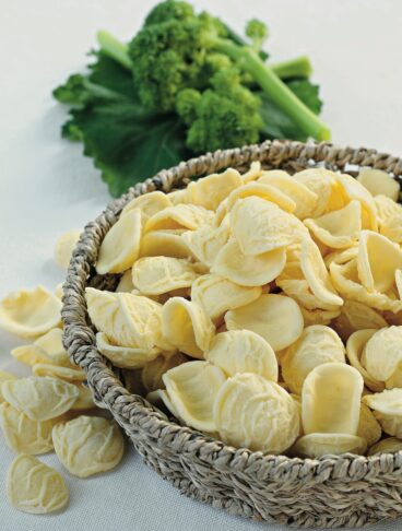 Cesto con orecchiette fresche e cime di rapa sullo sfondo