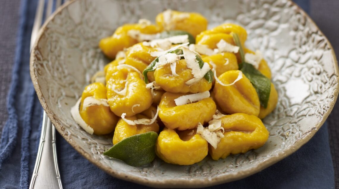 gnocchi di zucca in un piatto conditi con burro, salvia e formaggio