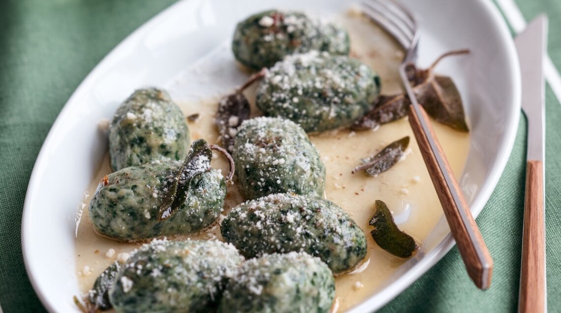 strangolapreti, gnocchi di spinaci su un piatto conditi con burro e salvia
