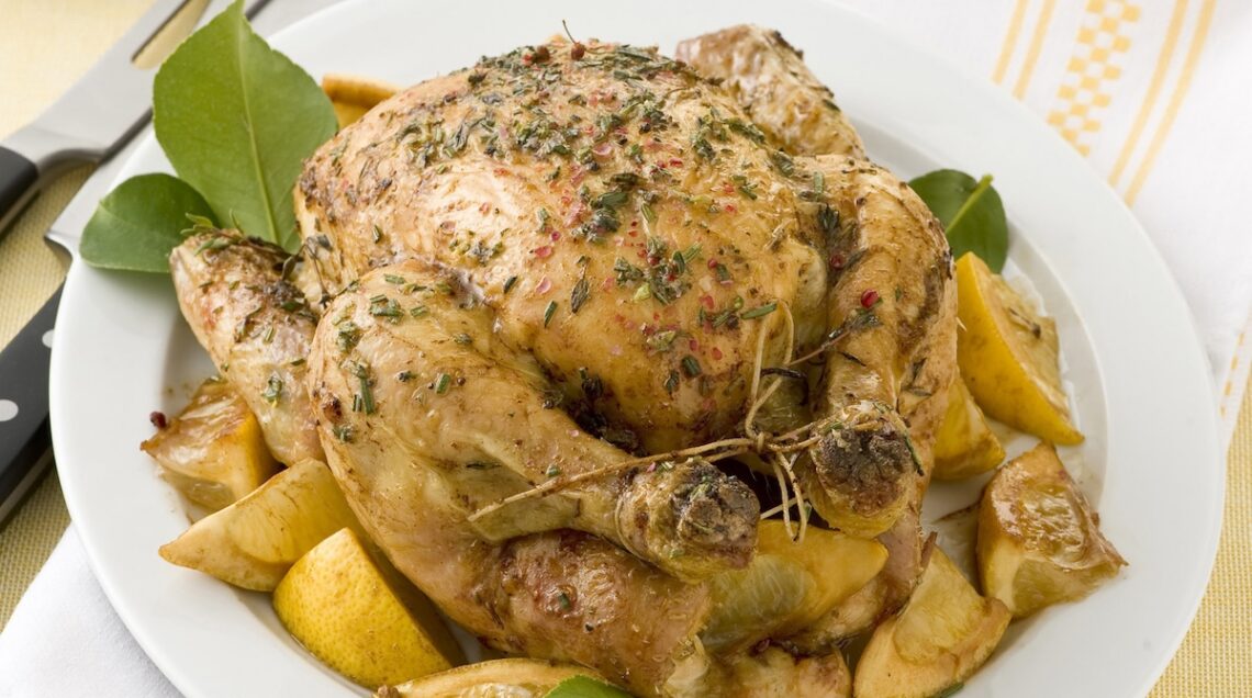 pollo arrosto alle erbe circondato da spicchi di limone