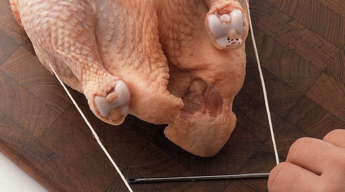 pollo crudo con due lembi di spago che escono dalle cosce