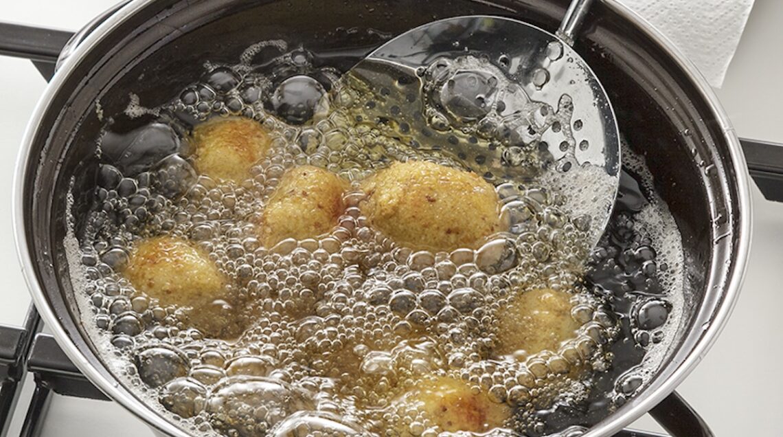 frittelle immerse nell'olio scaldato in padella, con schiumarola