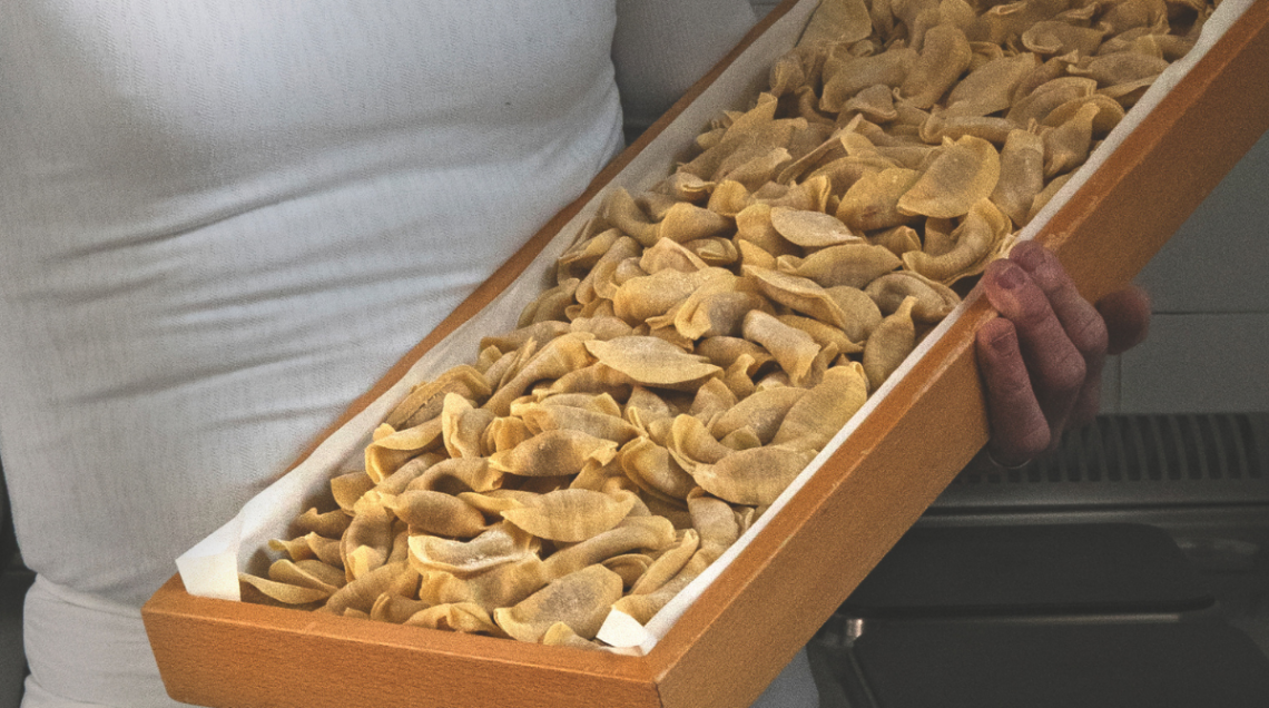 Una grande teglia in legno colma di pasta fresca ripiena fatta a mano, tipica della tradizione di Bergamo. 