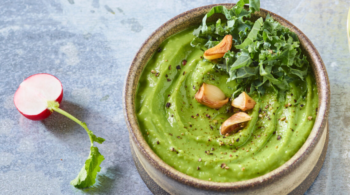 ciotola con hummus di fave, decorato con aglio e kale