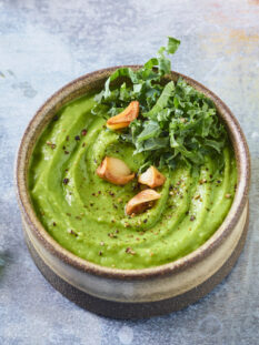 ciotola con hummus di fave, decorato con aglio e kale