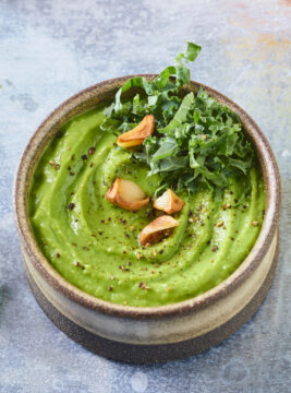 ciotola con hummus di fave, decorato con aglio e kale