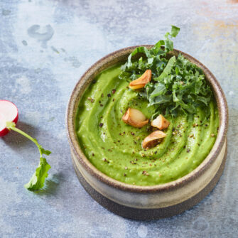 ciotola con hummus di fave, decorato con aglio e kale