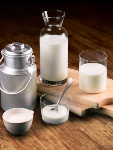 latte-intero-fresco-caraffa-vetro-e-bidone-alluminio-tradizionale-su-legno