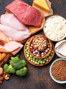 Composizione di carne, pesce, uova, legumi, cereali, latte e frutta secca su sfondo scuro