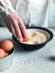 Mano che appoggia uovo nella farina