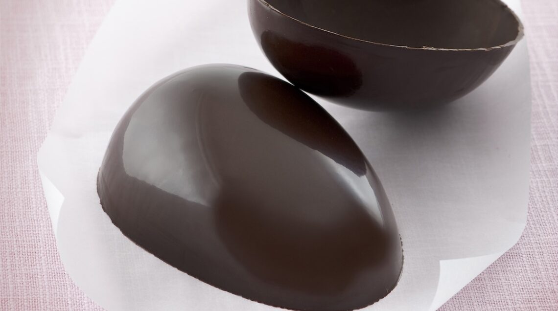 uovo di cioccolato diviso a metà su foglio bianco