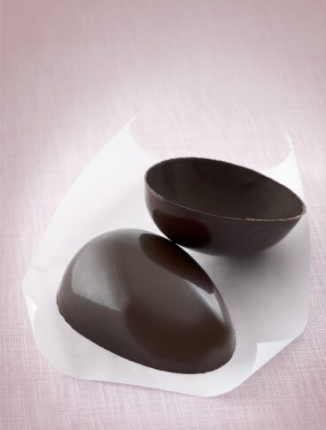 uovo di cioccolato diviso a metà su foglio bianco