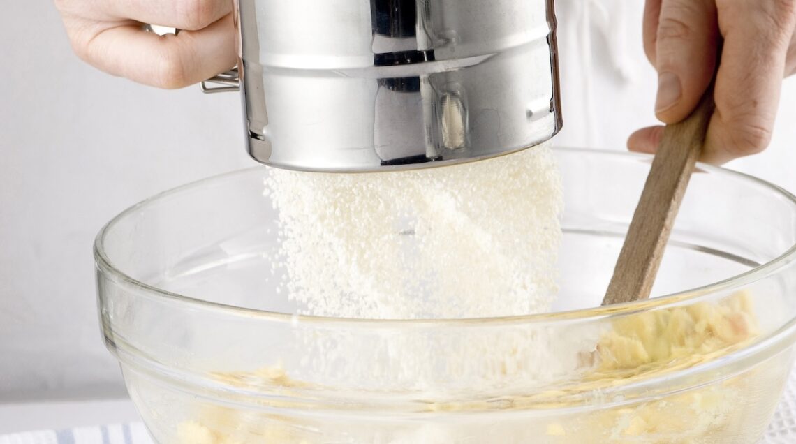 farina che scende da un setaccio su un impasto