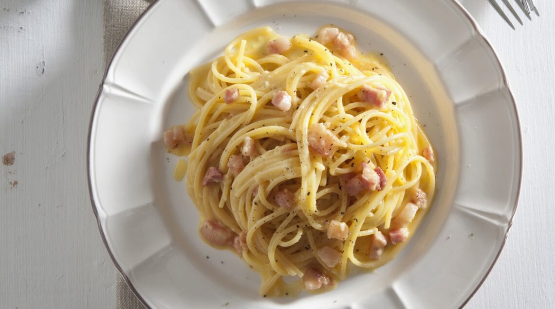 piatto di spaghetti alla carbonara con pecorino e grattugia