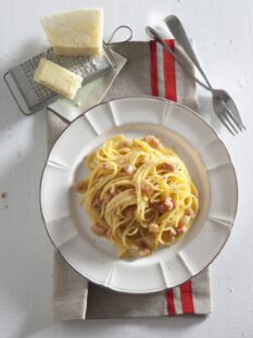 piatto di spaghetti alla carbonara con pecorino e grattugia