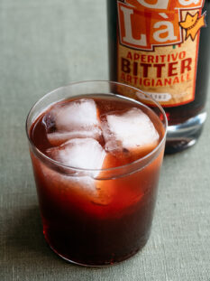 bicchiere con cocktail negroni e ghiaccio e bottiglia di liquore