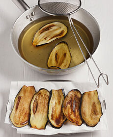 Fette di melanzane fritte e padella con olio per friggere