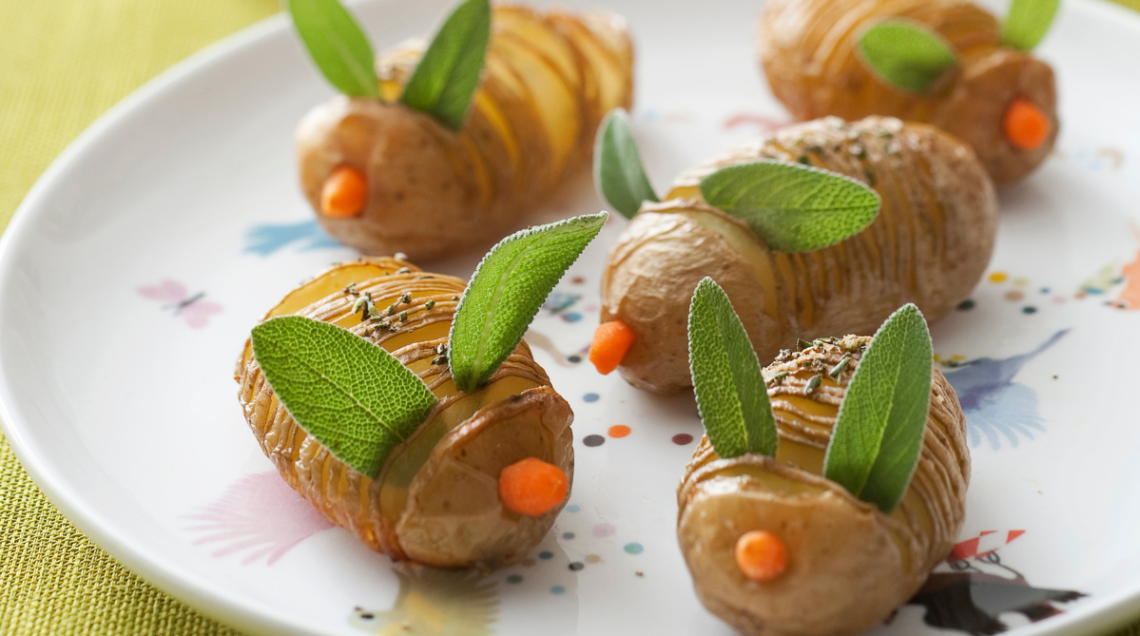 Patate al forno intagliate e decorate con foglie di salvia come orecchie e pezzetti di carota come naso