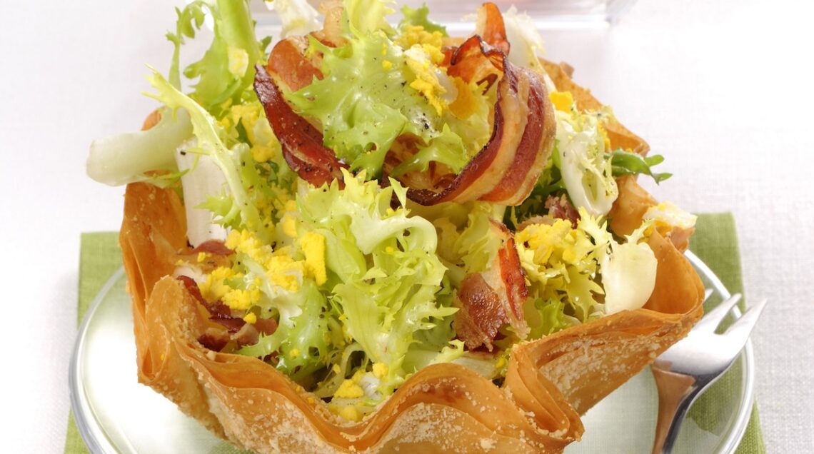 insalata riccia condita con pancetta e uova in un cestino di pasta