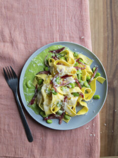 piatto di tagliatelle con crema di fave, fave, salame e pecorino