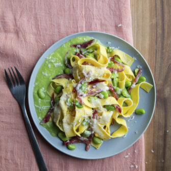 piatto di tagliatelle con crema di fave, fave, salame e pecorino