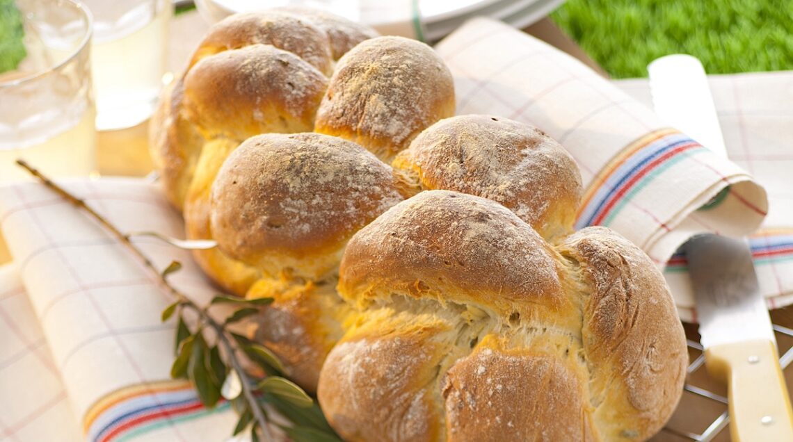 treccia di pane con rametto di ulivo su un prato verde