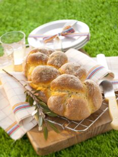 treccia di pane con rametto di ulivo su un prato verde