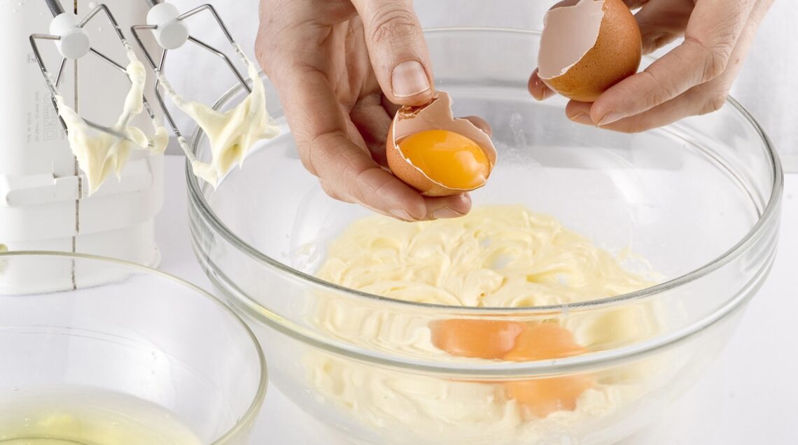 aggiunta uova a un impasto di burro e zucchero