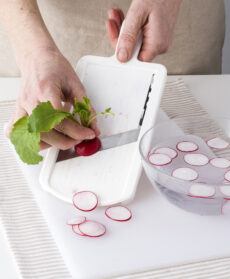 mano di chef che taglia i ravanelli con la mandolina