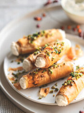 1 confezione di pasta fillo – 40 g di burro – 200 g di ricotta – 2 cucchiai di mascarpone – 80 g di formaggio blu di capra – 1 cucchiaio di miele – 50 g di granella di pistacchi – un mazzetto di erba cipollina – sale – pepe 1 Stendete la pasta fillo sul piano di lavoro e ritagliatela in strisce larghe 5-6 cm e lunghe quanto i fogli di pasta (circa 20-24 cm); spennellatele una alla volta con un po' di burro fuso, unite anche un pizzico di sale e arrotolatele intorno a cannelli di metallo con diametro di 1,5 cm foderati con carta da forno, sovrapponendo 4-5 strisce per ogni cannello e facendo in modo che la pasta non sia troppo stesa, ma crei qualche grinza morbida. 2 Sistemate i cannolini su una placca foderata con carta da forno e cuoceteli nel forno già caldo a 180° finché saranno ben dorati (circa 12-15 minuti). Lasciate intiepidire i cannolini prima di sfilarli delicatamente dai supporti. 3 Lavorate la ricotta con il mascarpone e il formaggio di capra, aggiungendo anche un pizzico di pepe a piacere. Farcite i cannolini con la crema di formaggio usando una sacca da pasticciere, quindi sporcate la superficie con un po' di miele e cospargeteli con la granella di pistacchi e l'erba cipollina tagliuzzata