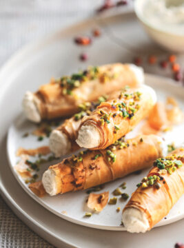 1 confezione di pasta fillo – 40 g di burro – 200 g di ricotta – 2 cucchiai di mascarpone – 80 g di formaggio blu di capra – 1 cucchiaio di miele – 50 g di granella di pistacchi – un mazzetto di erba cipollina – sale – pepe 1 Stendete la pasta fillo sul piano di lavoro e ritagliatela in strisce larghe 5-6 cm e lunghe quanto i fogli di pasta (circa 20-24 cm); spennellatele una alla volta con un po' di burro fuso, unite anche un pizzico di sale e arrotolatele intorno a cannelli di metallo con diametro di 1,5 cm foderati con carta da forno, sovrapponendo 4-5 strisce per ogni cannello e facendo in modo che la pasta non sia troppo stesa, ma crei qualche grinza morbida. 2 Sistemate i cannolini su una placca foderata con carta da forno e cuoceteli nel forno già caldo a 180° finché saranno ben dorati (circa 12-15 minuti). Lasciate intiepidire i cannolini prima di sfilarli delicatamente dai supporti. 3 Lavorate la ricotta con il mascarpone e il formaggio di capra, aggiungendo anche un pizzico di pepe a piacere. Farcite i cannolini con la crema di formaggio usando una sacca da pasticciere, quindi sporcate la superficie con un po' di miele e cospargeteli con la granella di pistacchi e l'erba cipollina tagliuzzata